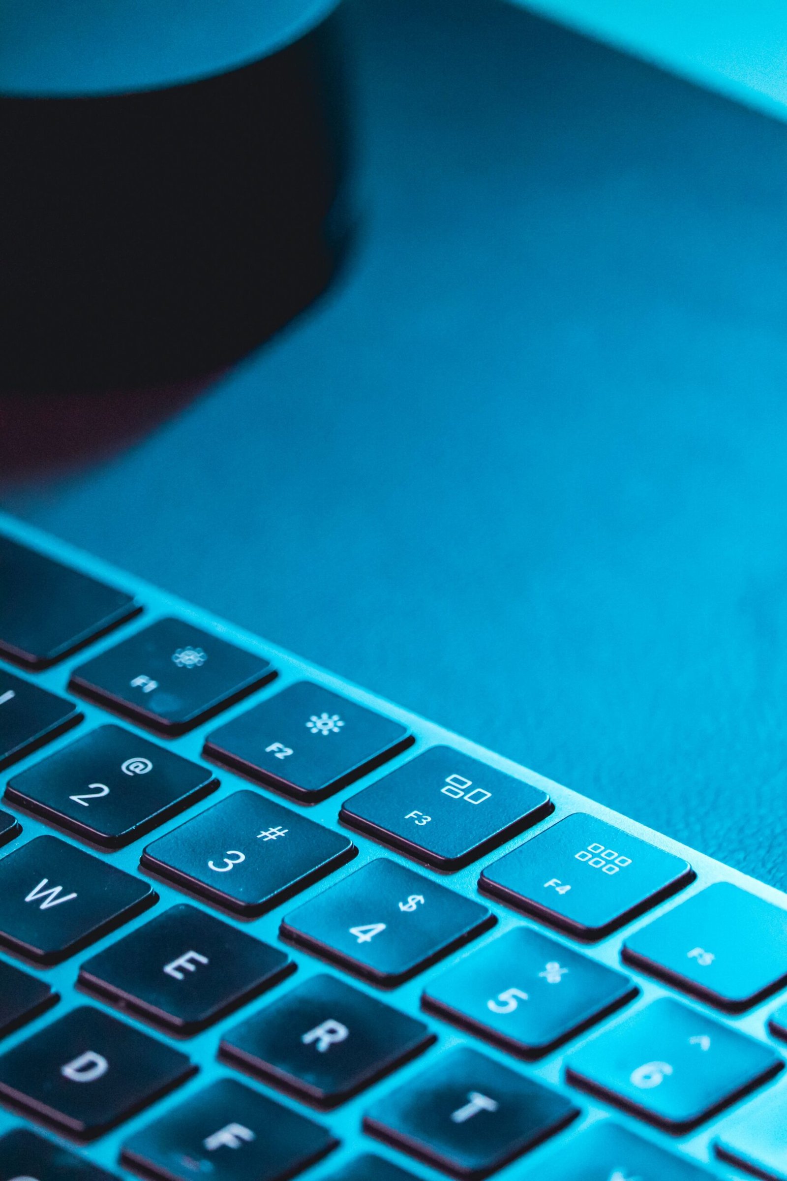 A close-up view of a computer keyboard illuminated by blue light, highlighting the keys.
