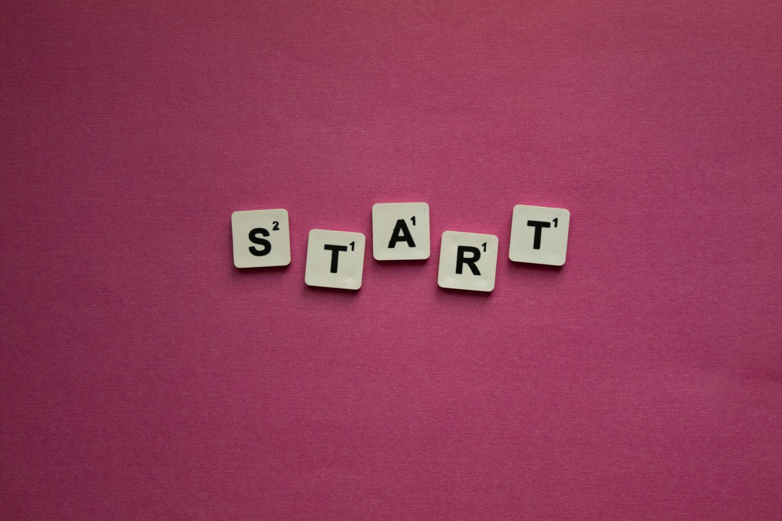 Scrabble tiles spelling 'START' against a pink background. Perfect for motivational themes.