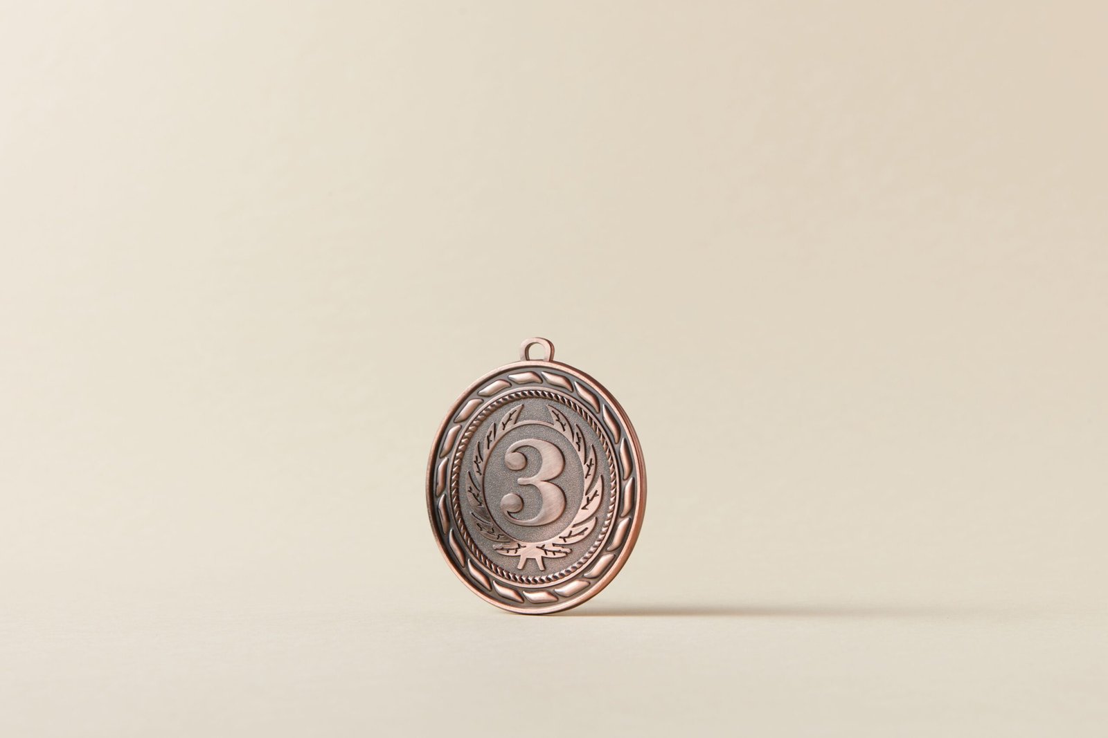 Close-up of a bronze medal with a number three on a plain white background.